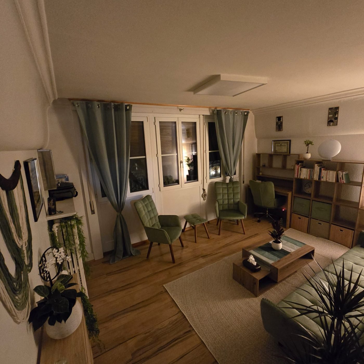 Salle de consultation en lumière tamisée : canapé et fauteuils verts